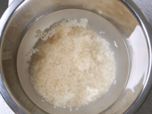 Basmati Reis in Schüssel mit kaltem Wasser waschen