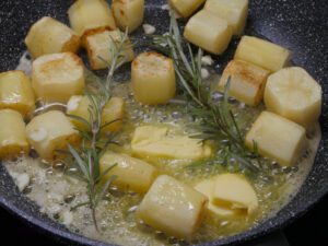 Butter zu den Kartoffeln geben und Rosmarin dazulegen