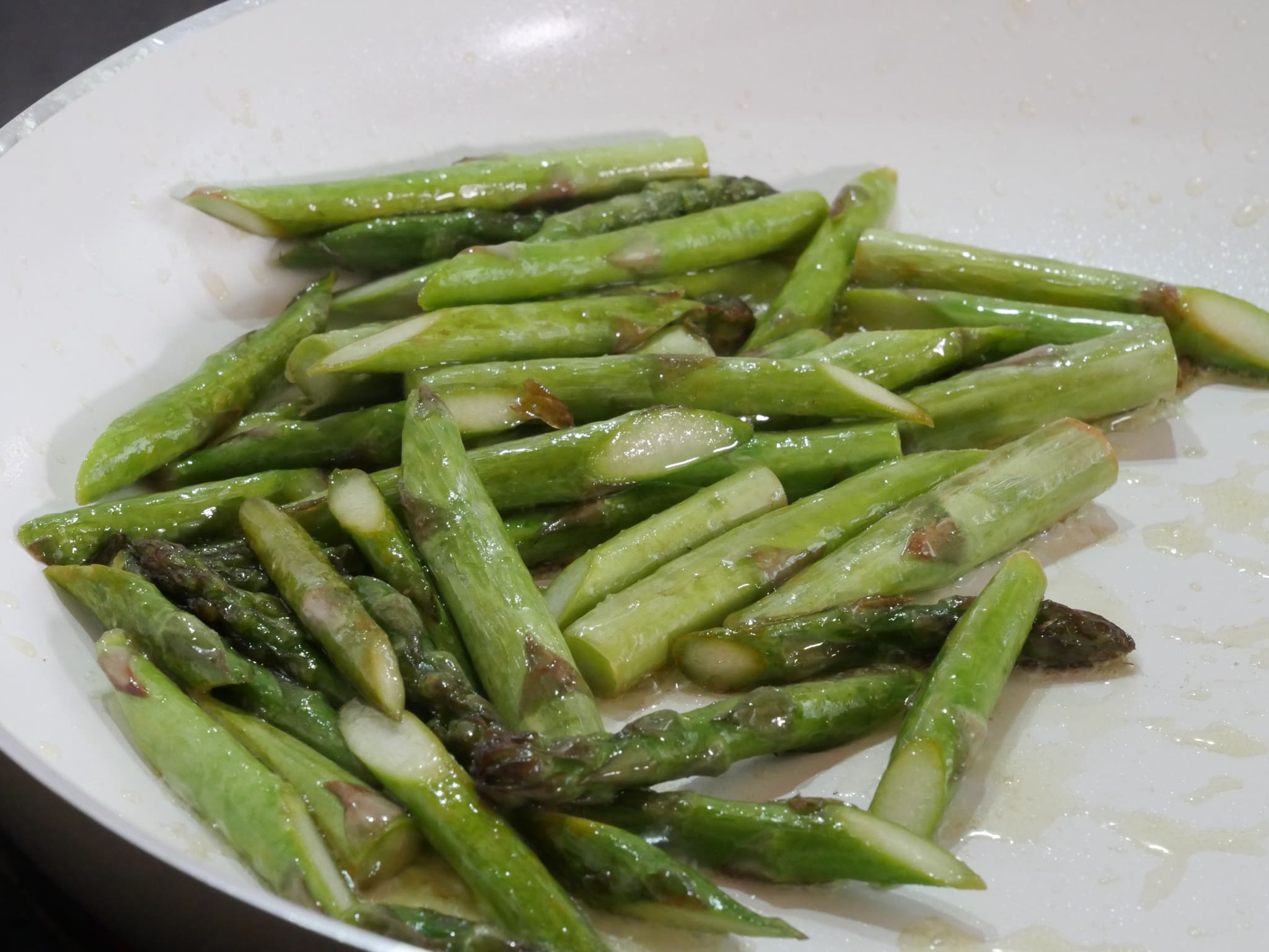 Butter zum gebratenen grünen Spargel geben