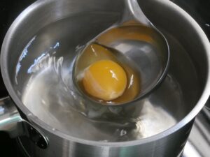 Ei aus der Kelle langsam in den Strudel gleiten lassen
