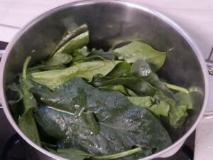 Frischen Spinat zu den Schalottenwürfeln geben