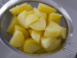 Gar gekochte Kartoffeln für Püree in einem Sieb abtropfen