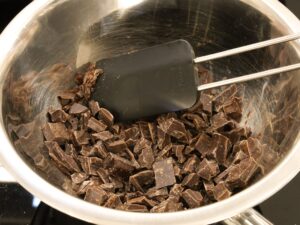 Gehackte Schokolade über einem Wasserbad für Mousse au chocolat schmelzen