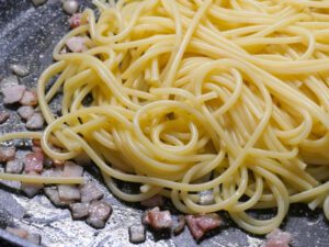Gekochte in Spaghetti zum Speck in die Pfanne geben