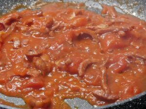 Geschälte Tomaten für Pasta Calabrese dazugeben und köcheln lassen