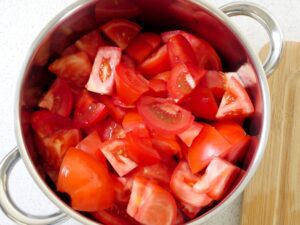 Grobe Tomatenstücke in einen Topf geben und mit Salz und Zucker vermengen