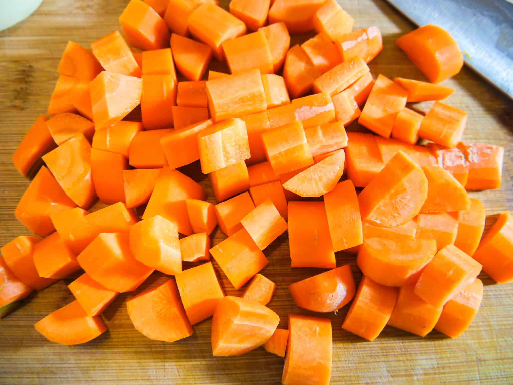 Karotten für eine leichte Kürbissuppe in Würfel schneiden