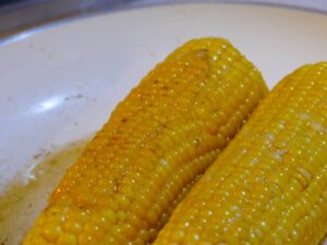 Maiskolben bekommen Farbe in Butter beim braten