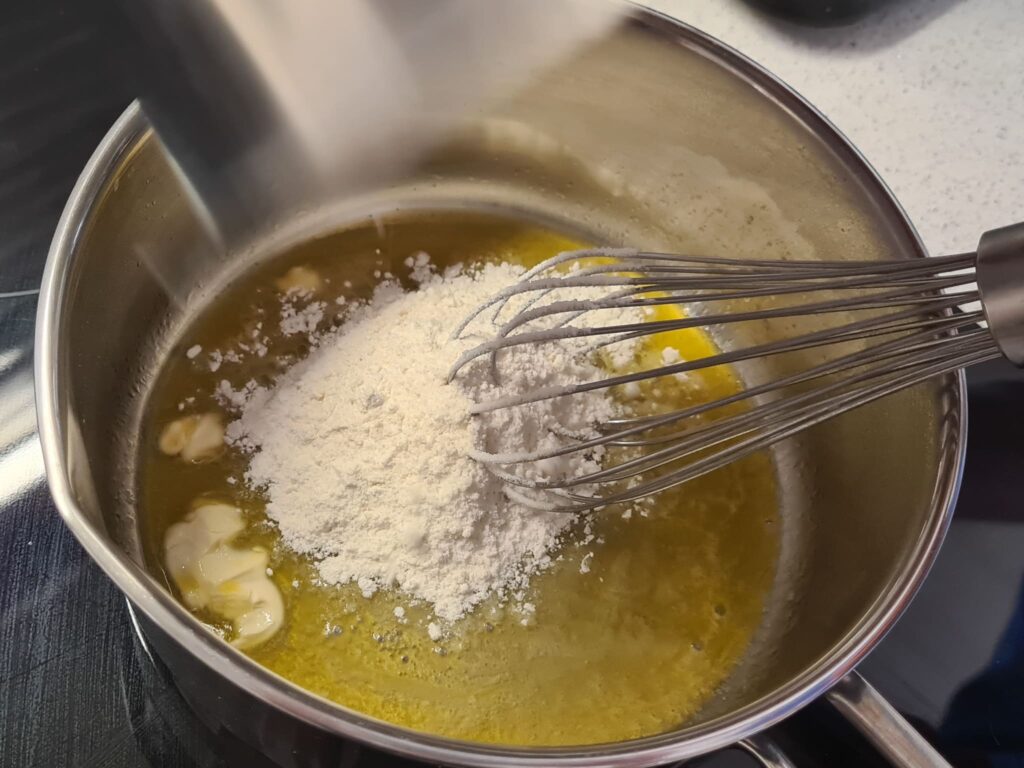 Mehl zur geschmolzenen Butter geben um Bechamelsauce herzustellen