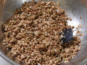 Roggenflocken für Granola mit Eiweiß und Honig vermengen