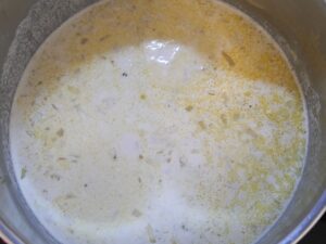Sahne und Brühe zu den Zwiebeln geben für Maronensuppe