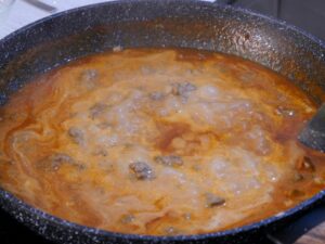 Sauce für Kritharaki-Auflauf aufkochen lassen lassen und Sahne hinzugeben