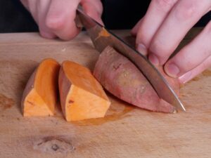 Wedges aus geviertelten Süßkartoffel schneiden