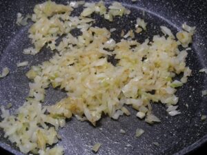 Zwiebeln und Knoblauch in Pfanne anschwitzen für Paprika Sahne Hähnchen